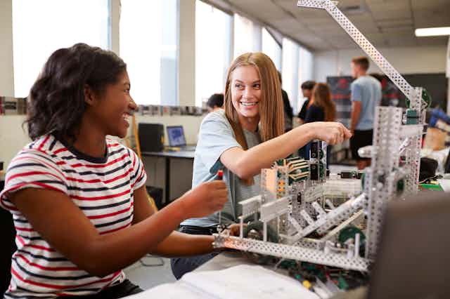 Two female students looking happy in a robotics class