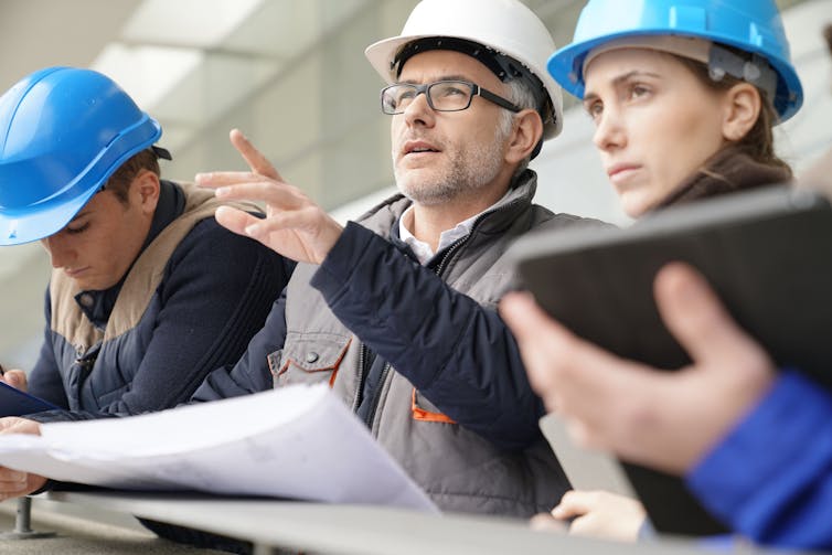 Older male engineer and young male and female engineers discuss a project