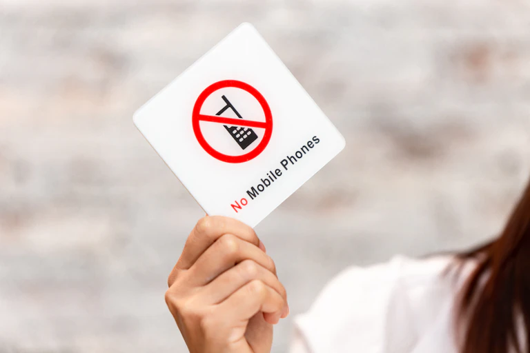 Girl holding up sign saying 'no mobile phones'