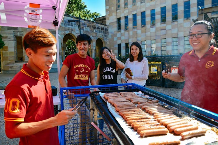 students look at sausages being barbecued