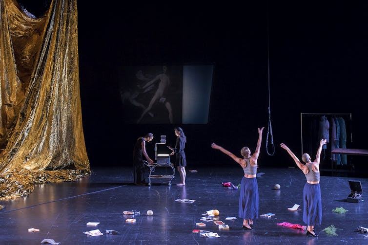 Two women dance in front of an overhead projector