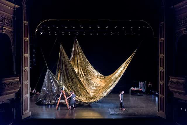 A vast stage. A gold curtain. Two women.