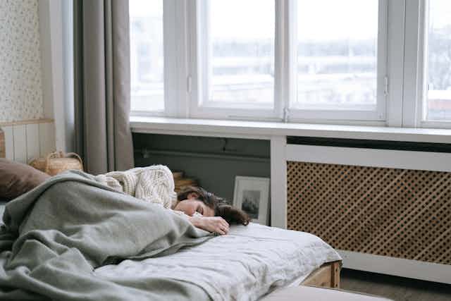 'Mujer durmiendo de día con una ventana de fondo'