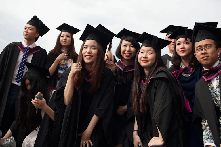A group of young Chinese graduates in academic caps and gowns after graduating from the UNiversity of the Arts in London.