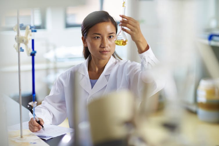 A Chinese scientist examines a flask in a laboratory.