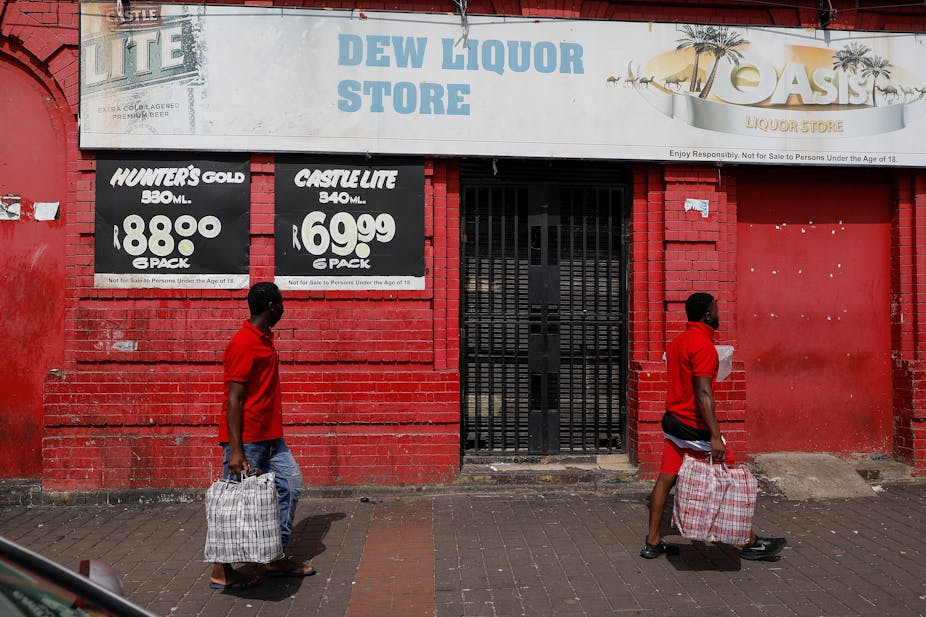 people walking past a closed liquor store