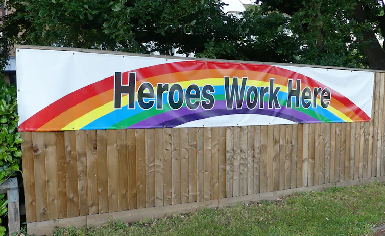 The fence of a care home with a banner saying 'Heroes Work Here' against a rainbow.