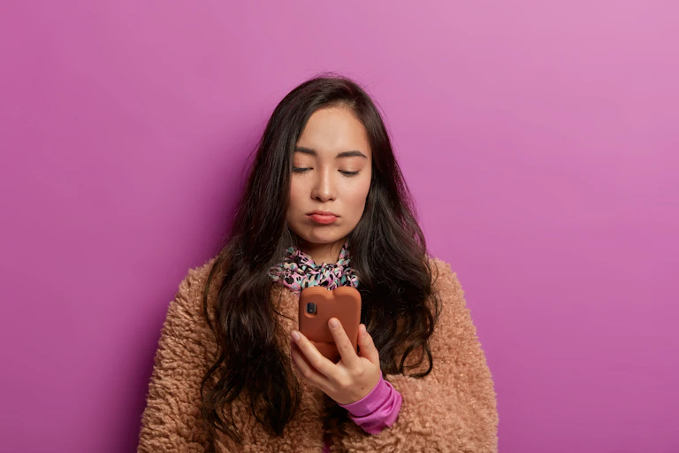 A woman looking unhappy while looking at her phone.