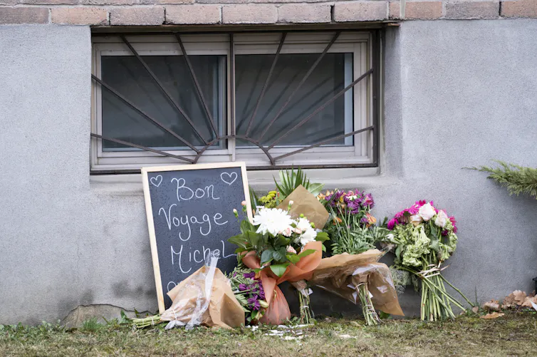 Flowers propped up against a wall with a chalkboard that reads 'Bonne Voyage Michel'