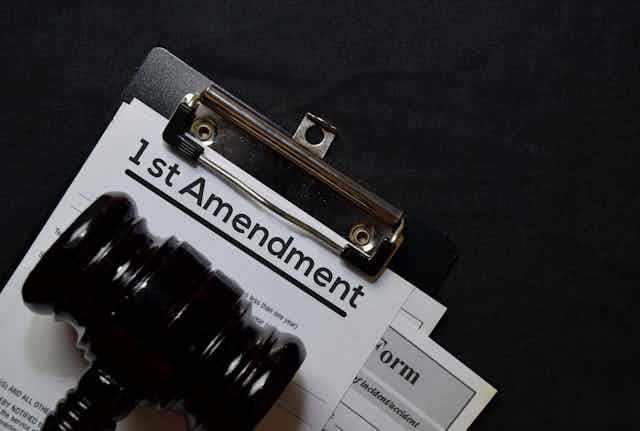 A clipboard with a page that says "1st Amendment" on it, under a judge's gavel