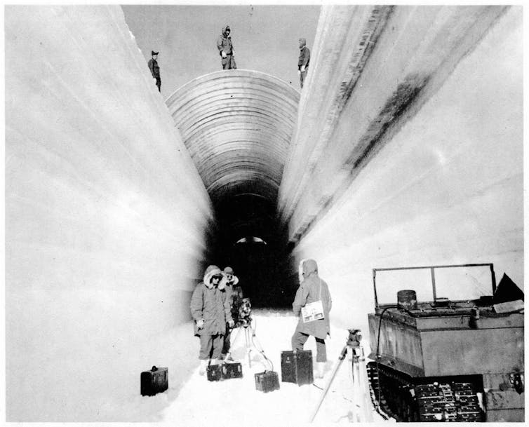 Workers cover a trench to build the under-ice military base