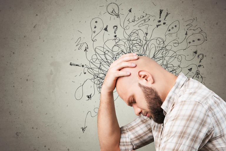 Man with his head bowed, with cartoon doodles surrounding his head