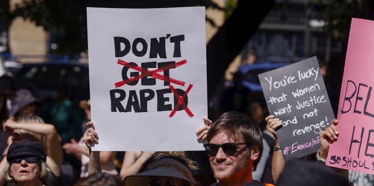 A woman at a rally holds up a protest sign.