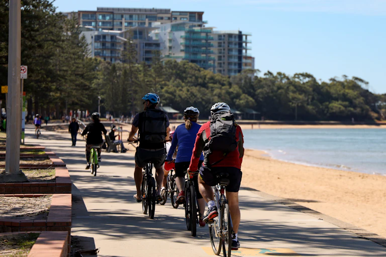 tourists riding bikes along beach in city
