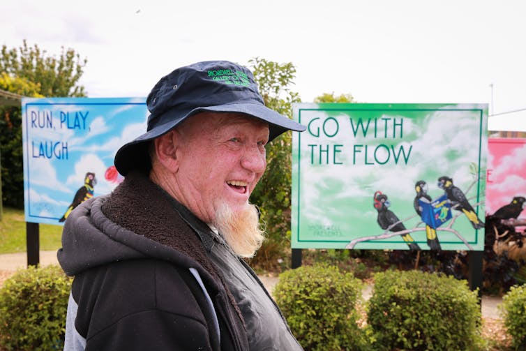 A man smiles in front of a billboard reading 