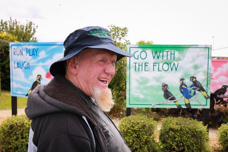 A man smiles in front of a billboard reading