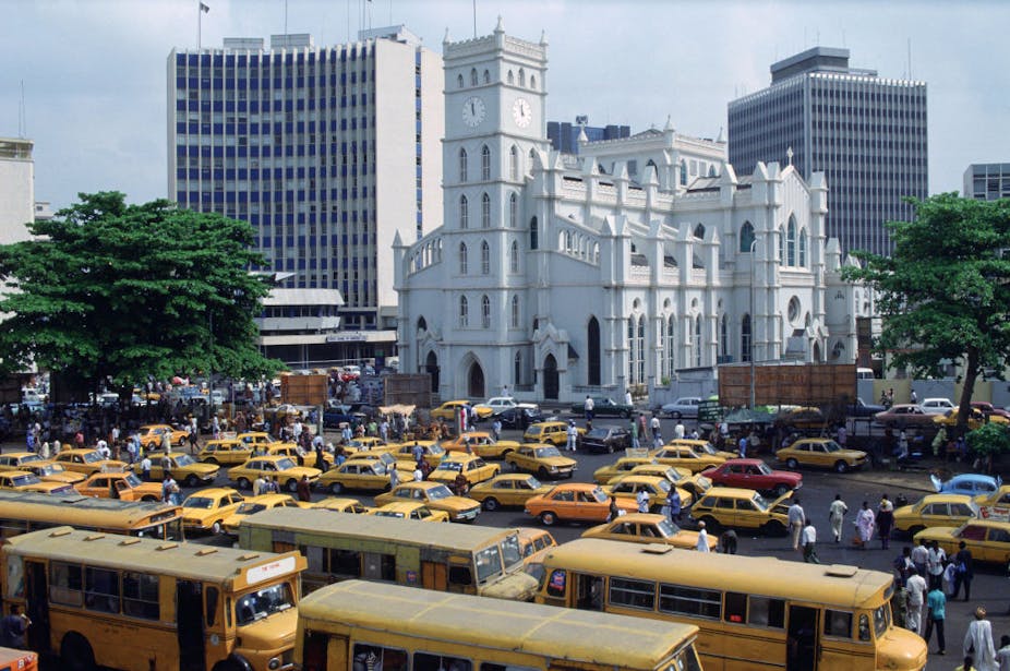Commercial vehicles ply the Lagos business district with several tall bank buildings.