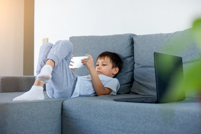 Boy watching something on phone on the couch.