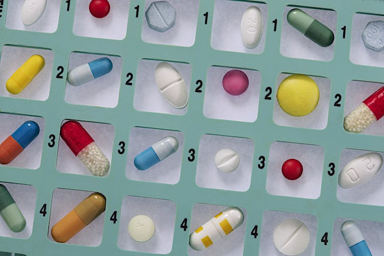 Pastillas de colores diversos en un pastillero cuadriculado y numerado.