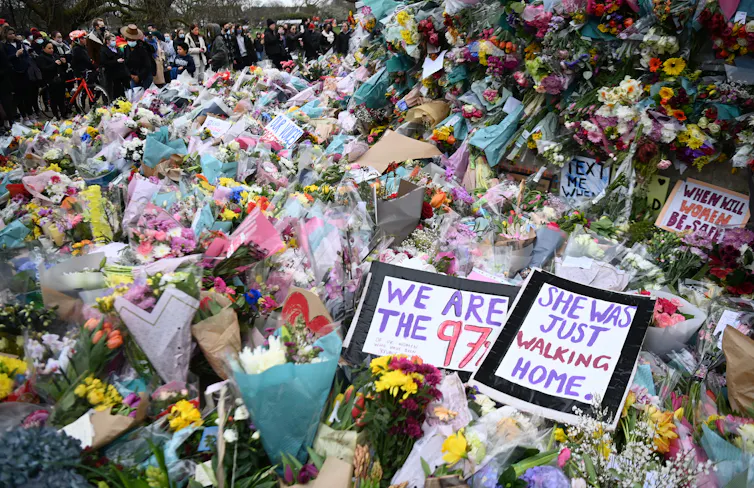 Flowers outside vigil for Sarah Everard with signs reading 'we are the 97 per cent' and 'she was just walking home'