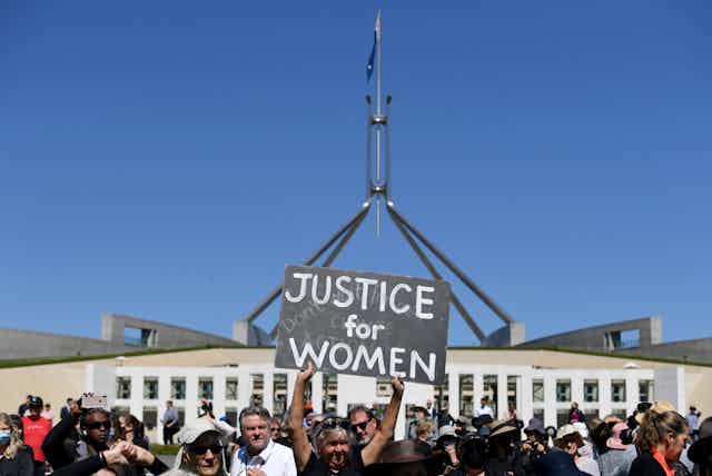 March4Justice protestors outside parliament house, one holding a sign which reads "Justice for Women"