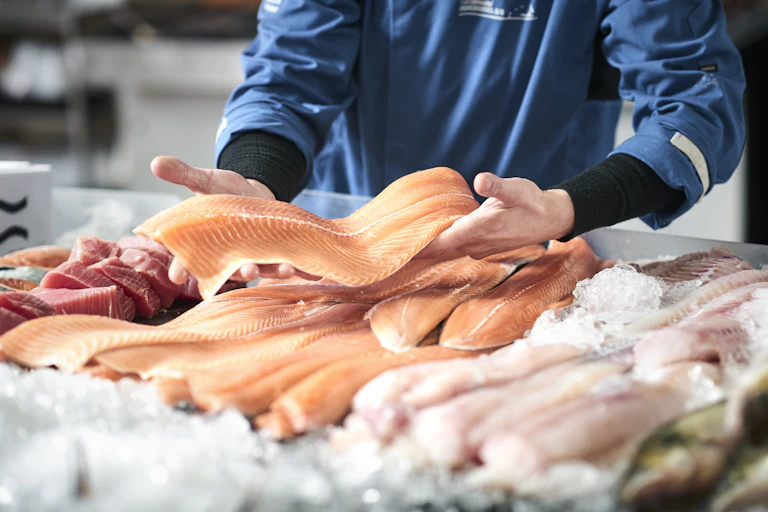 A fishmonger presents a salmon fillet.