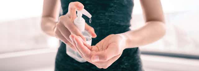 Image of a woman using hand sanitiser.