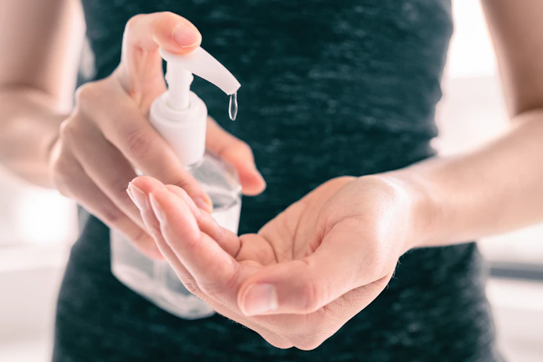 Image of a woman using hand sanitiser.