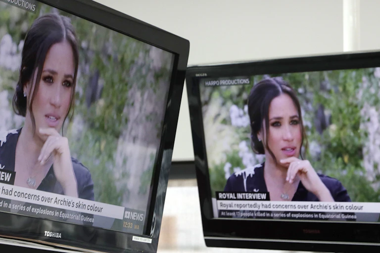 Meghan Markle is seen on two TV screens.
