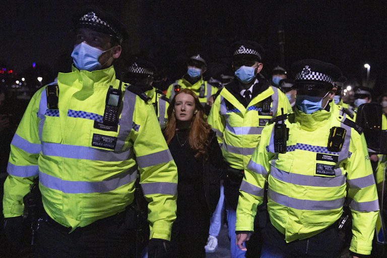 A protester is flanked by five police officers in Clapham.