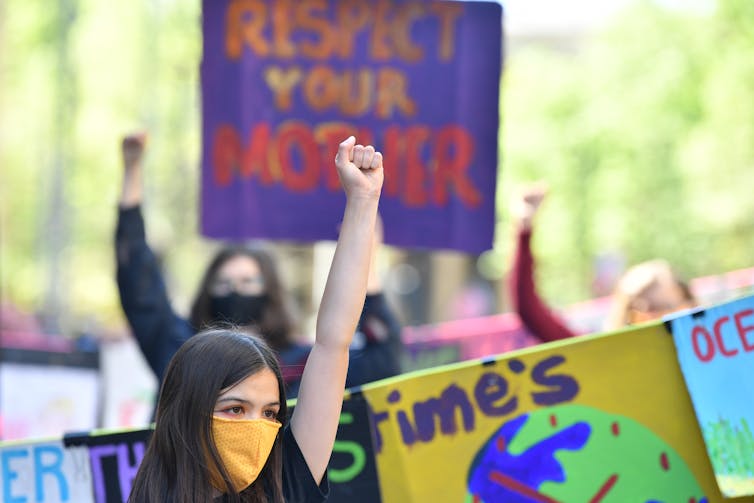 Girl in mask raises fist at climate rally