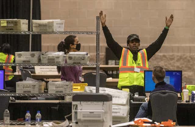 An election worker surrounded by boxes of mail-in ballots inside a convention center after Election Day