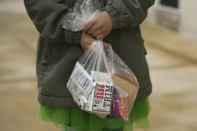 Child carries lunch in plastic bag