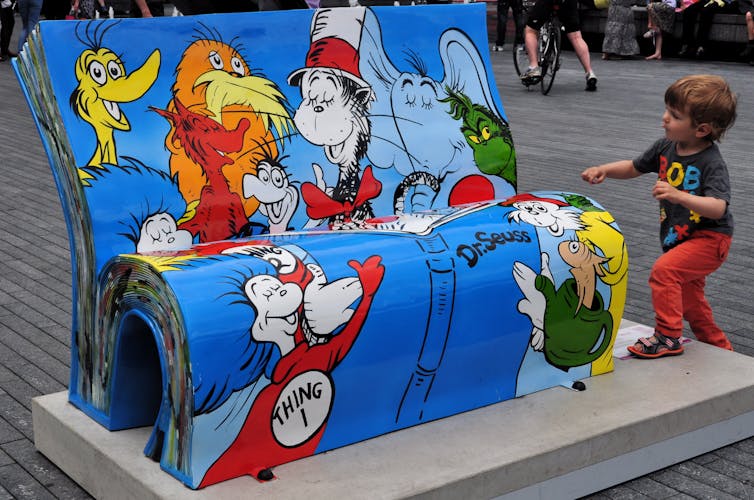 A child approaches a Dr. Seuss BookBench sculpture