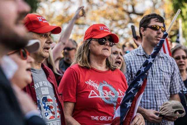 QAnon supporters stand in Trump gear with American flags