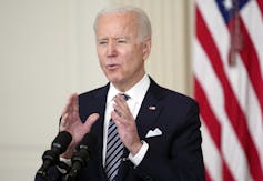 Biden speaks at a podium with the American flag behind him.