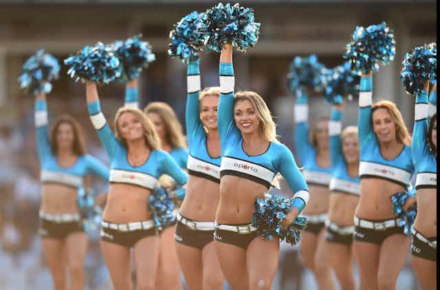Cheerleaders in skimpy outfits with pom poms.