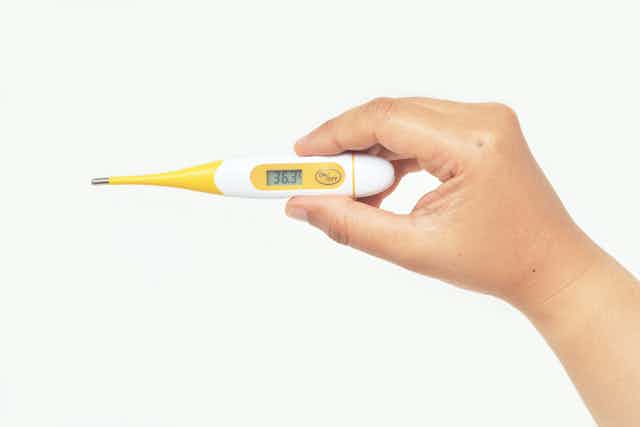 Child holds a yellow thermometer.