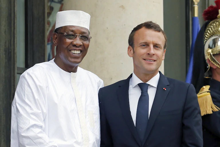 A man black in white Muslim garb greets a white man in a blue suit