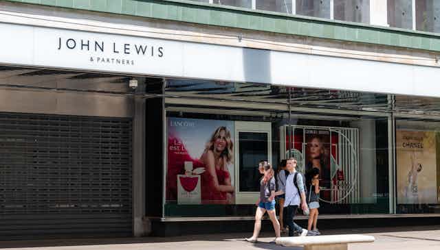 A couple walk past a closed John Lewis department store.