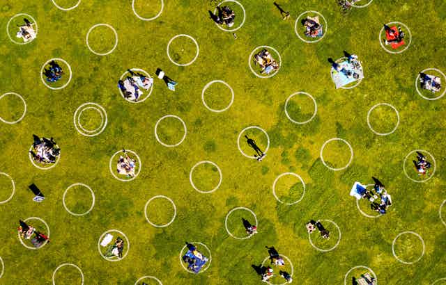 White social distancing circles painted on grass