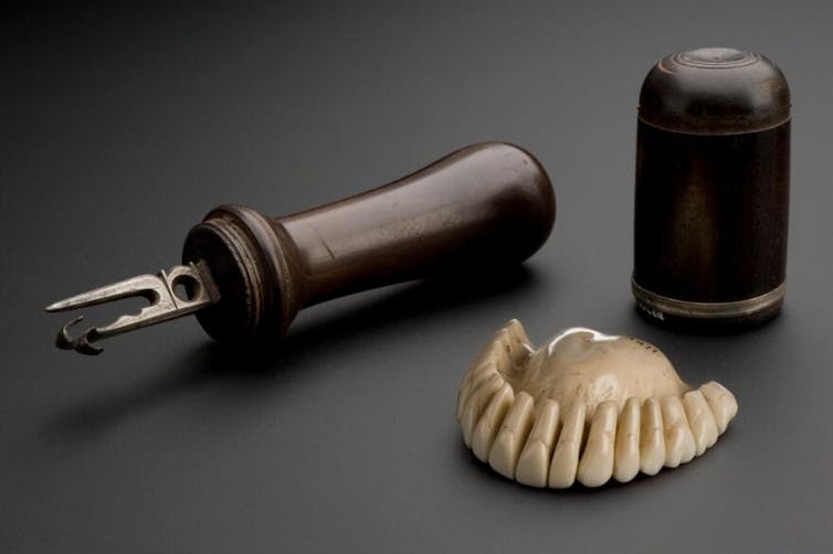 Set of ivory teeth and wooden tools on grey background.