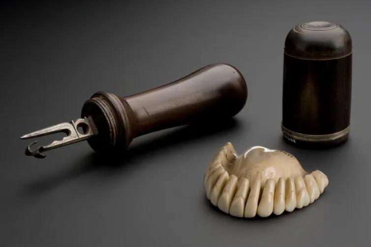 Set of ivory teeth and wooden tools on grey background.