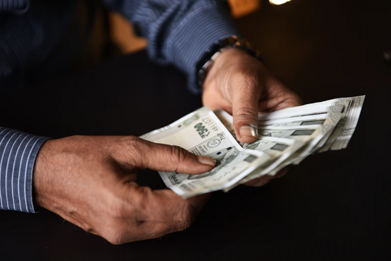 Man's hands are holding Indian rupee banknotes.