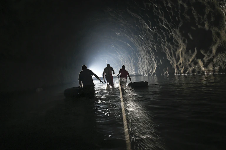 Three men walk through a dark tunnel