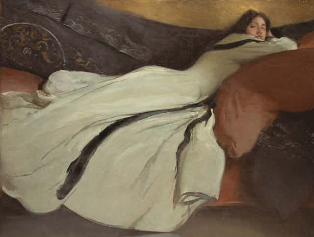 A woman in a flowing dress lies in repose.