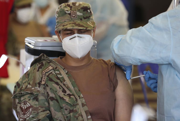 An Air Force member closes her eyes while getting a vaccination.