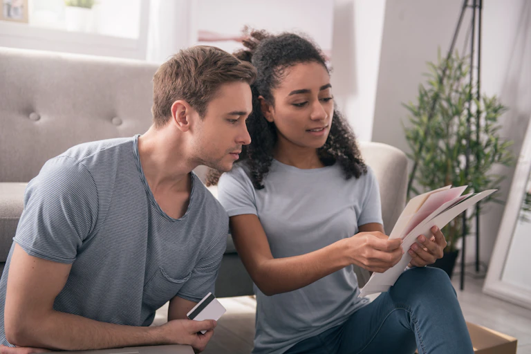 Couple looks over some papers together while he holds a credit card.