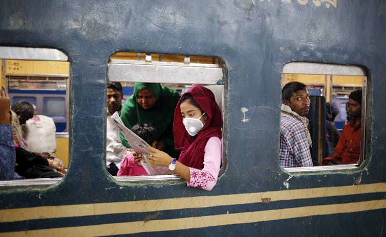 Girl reading newspaper in a crowded train in Balgladesh.