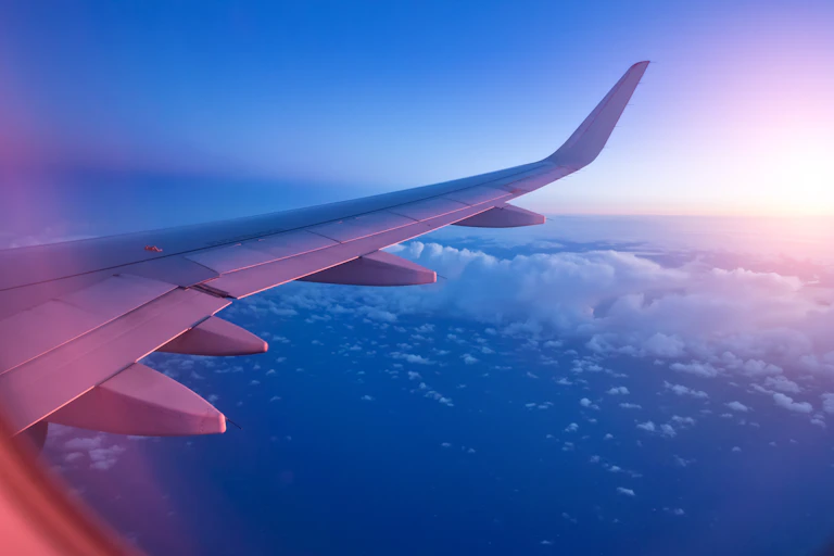 view of plane wing over sea and clouds